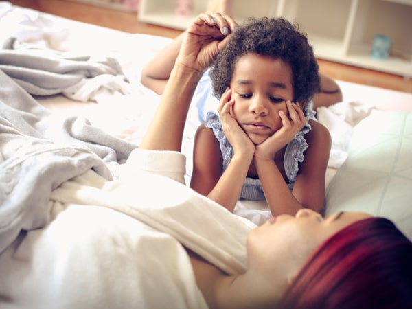 Women on bed talking to child.