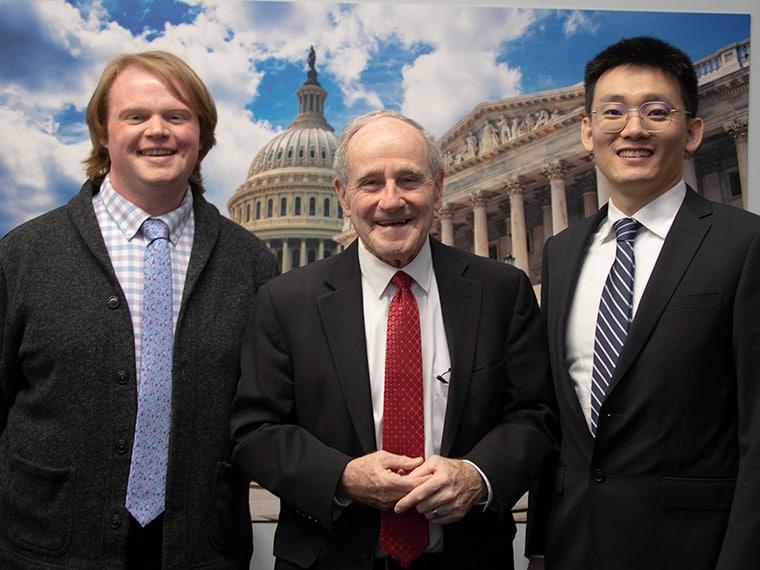 Cody Wolf, Idaho Senator James E. Risch, and Rui Li, MD, PhD standing in front of a backdrop of the U.S. Capitol building during  AACR's Early-career Hill Day.