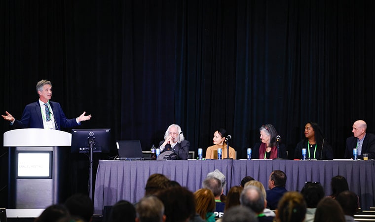 Dr. William G. Nelson standing at podium during the special session on “Strategies to Effectively Communicate Science to the Public.” The rest of the panelists are seated a table, from left to right: Dr. Philip D. Greenberg, Dr. Lisa A. Newman, Dr. Mary C. Beckerle, Dr. Bianca Islam, and Clifton Leaf.